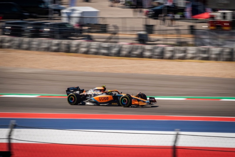 A papaya-orange McLaren Formula 1 car driven by Lando Norris cornering at speed at the Circuit of the Americas