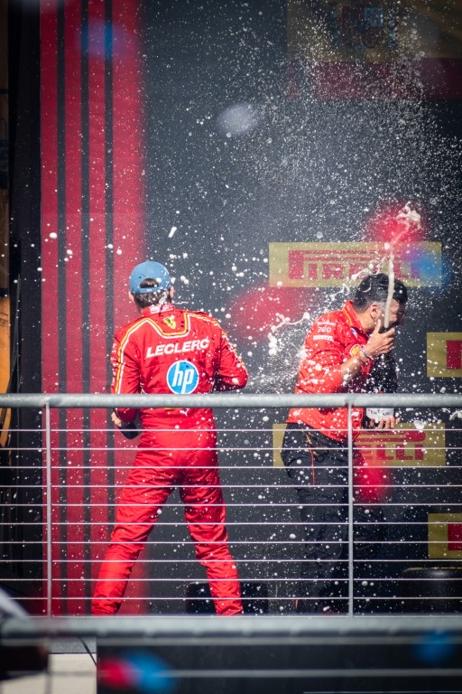 Charles Leclerc sprays champagne on to a Ferrari team member
