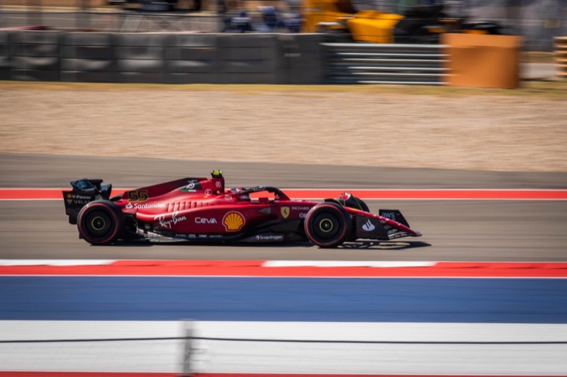 A red Ferrari Formula 1 driven by Carlos Sainz at speed in profile, blurred with motion, at the Circuit of the Americas