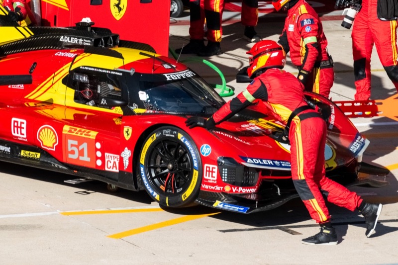 Mechanics in red suits servicing the number 51 Ferrari 499P Hypercar during a pit stop