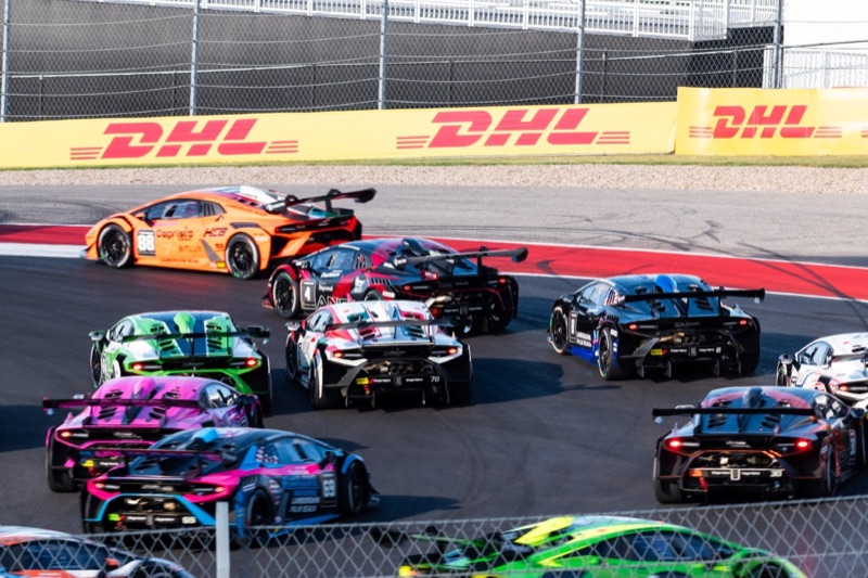 A colorful field of Lamborghini GT race cars battling into turn 1 at the Circuit of the Americas